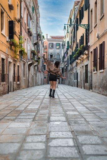 A rear view of a cheerful dancing and walking along the central streets of Venice, vertical