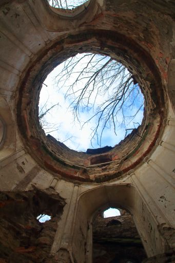 A low angle vertical shot of a ruined building with blue sky in the background