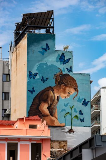 A vertical shot of a beautiful street art of a little girl on the sidewall of a building in Athens