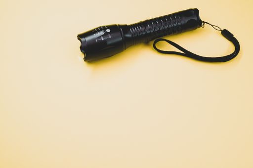A high angle shot of a flashlight on a yellow surface