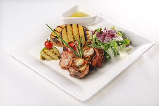 An isolated shot of a plate with pork with tomatoes and salad - perfect for a food blog or menu usage