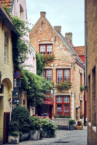A vertical shot of a street cafe in old brick buildings in Bruges, Flanders, Belgium