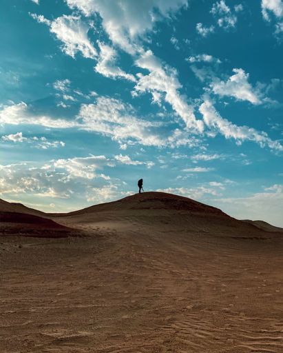 A vertical of a man's silhouette on Sand Dunes in Shipwreck Beach, United Arab Emirates
