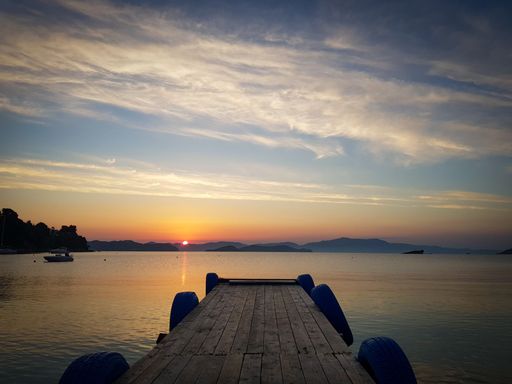 A wooden pier over a lake under a cloudy sky at sunset