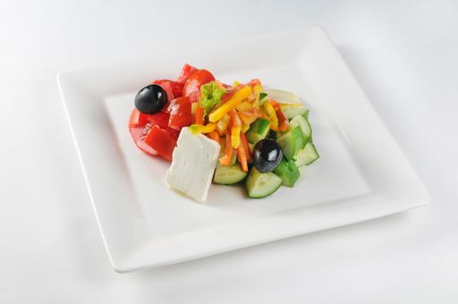 An isolated shot of a white plate with Greek salad - perfect for a food blog or menu usage