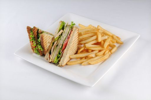 An isolated shot of a white plate with a club sandwich and french fries -  perfect for a food blog or menu usage