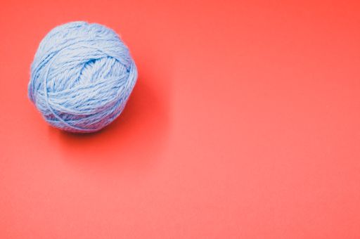 A high angle shot of a ball of yarn on a red surface