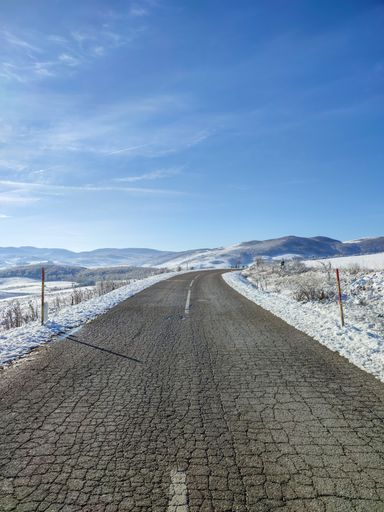 A vertical shot of a highway road through the snowy field