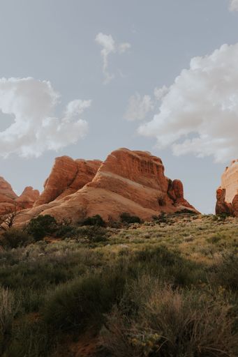 A vertical shot of a canyon under a cloudy sky with grass in the foreword