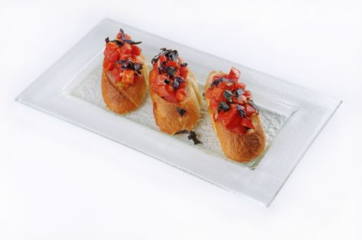 An isolated shot of a white plate with three classic bruschettas - perfect for menu usage