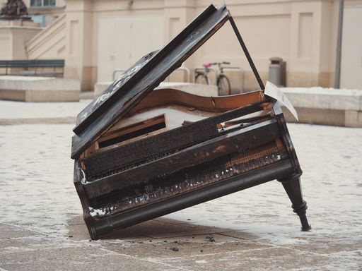 A broken piano standing on only one leg captured outdoors