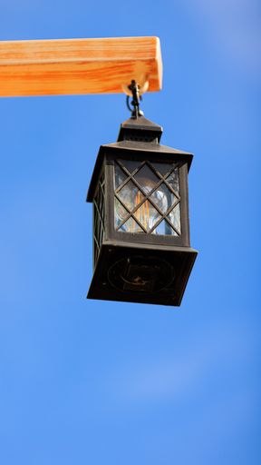 A vertical low angle shot of a hanging vintage lamp on a wooden pole