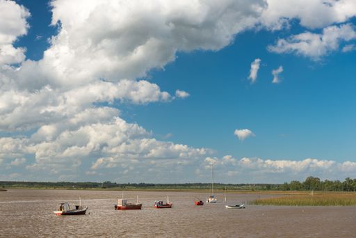 A drone shot of fishermen's boats on the surface of a lake under the blue cloudy sky
