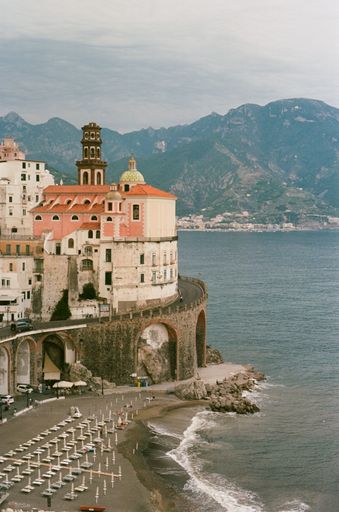 A vertical shot of the Collegiate Church of St. Mary Magdalene in Salerno, Italy with mountains and the sea in the background.