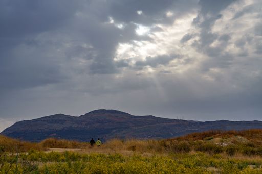 a couple seen from the back walking in the countryside at dawn under a cloudy stormy sky