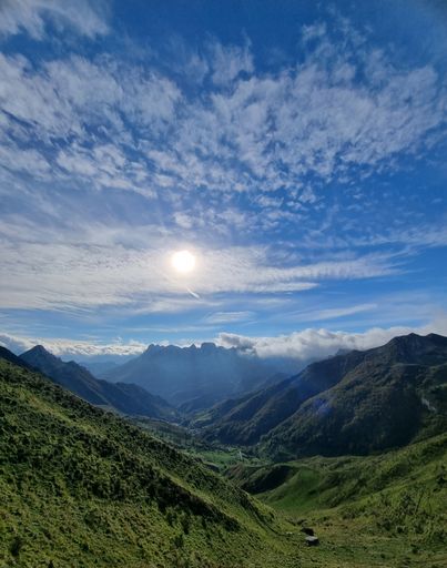 A vertical shot of green hills under a blue sky with clouds in Asturias, Spain.