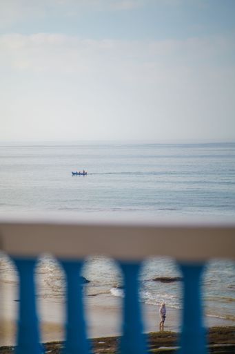 A vertical shot of a boat at a distance with blur fence in the foreground