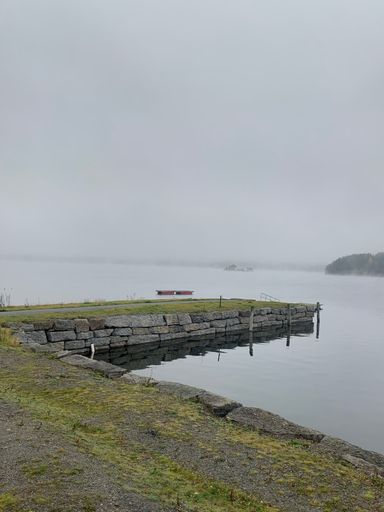 A piled stone dock and calm lake on a foggy day