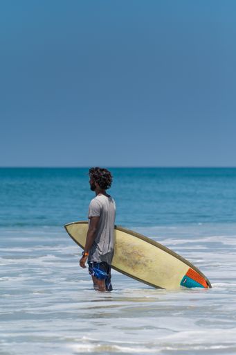 An Indian Male with his Surf Board waiting for the waves in the ocean