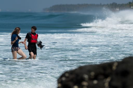 Two Photographers walking on the beach to capture the surfers in Action