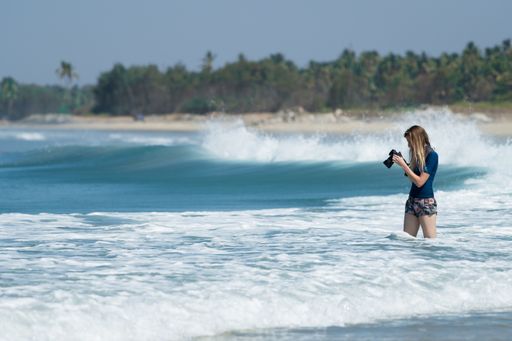 A female Photographer looking at her Camera screen and reviewing the images in the beach