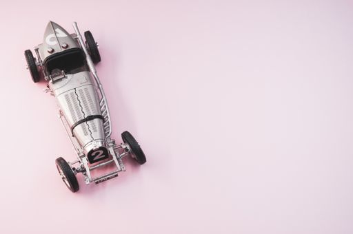 A high angle shot of a small collectible car on a pink surface