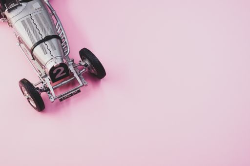 A high angle shot of a small collectible car on a pink surface