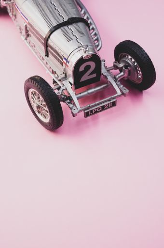 A vertical shot of a small collectible car on a pink surface