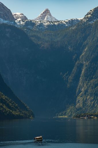 A vertical shot of a tourism ship sailing on a lake near mountains in Berchtesgaden, Germany