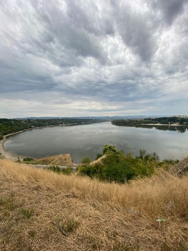 A vertical shot of fluffy clouds over the landscape with a lake