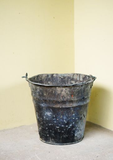 An Old rusty bucket by a wall