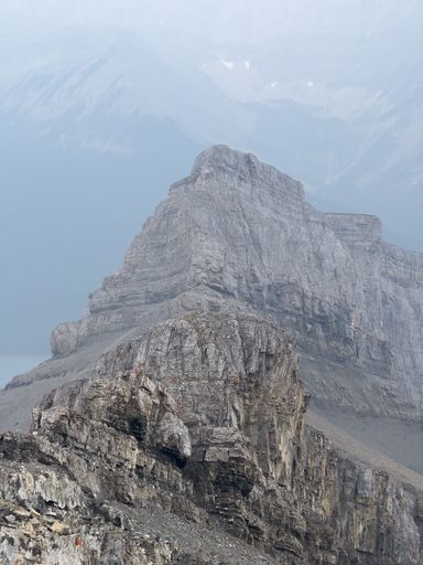 A beautiful view of steep rocky mountains under a cloudy sky on a misty day in the wilderness