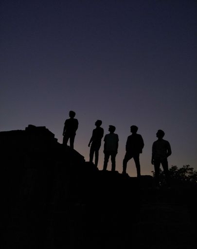A vertical shot of silhouettes of people standing on a hill under the beautiful night sky