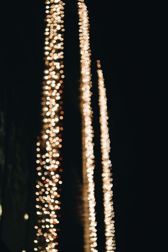 A vertical selective focus shot of golden bokeh lights spreading beauty during nighttime