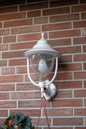 A vertical shot of a white lamp hanging on a wall