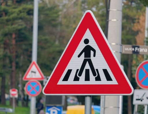 A red pedestrian crossing sign on a blurred background