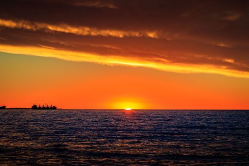 A beautiful sunset reflected in the water with sailing ships in Fremantle port city