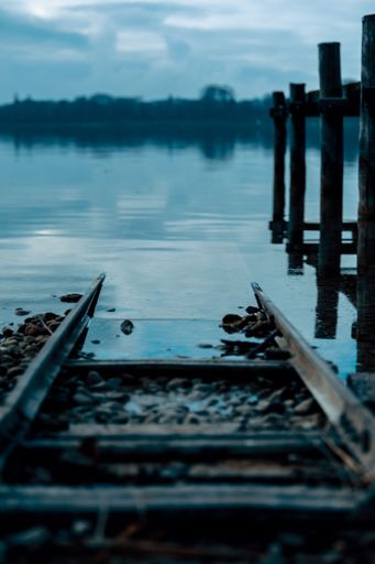 A vertical shot of an old broken and abandoned railroad leading out into the foggy Lake