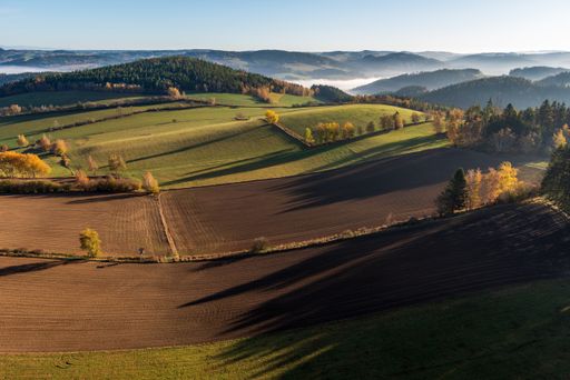 An aerial shot of a beautiful green landscape with a lot of trees and grassy hills