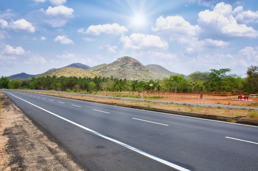 A Highway from Tirichi to Madurai, South India with trees around under a cloudy sky