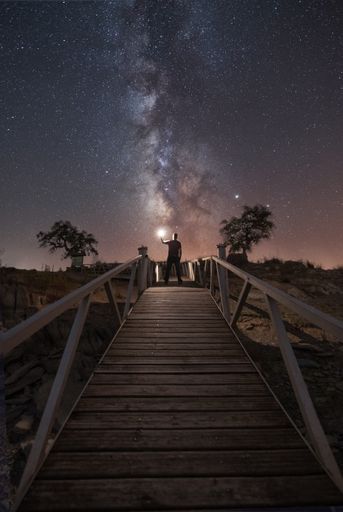 A vertical shot of a wooden dock under the Milky Way Galaxy in Spain
