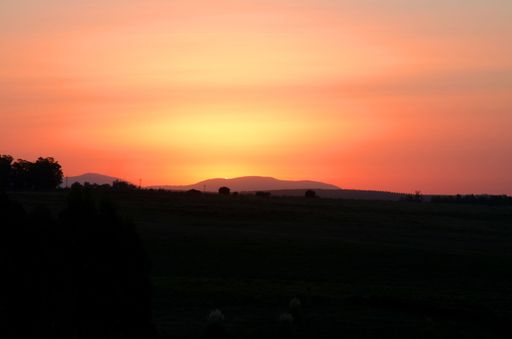 The silhouettes of hills against the background of the bright orange sky at sunset.