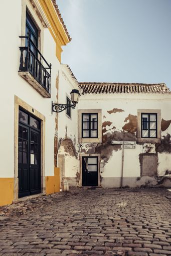 View on one of the cozy cobblestoned alleys of Faro in Portugal. Muted atmospheric color