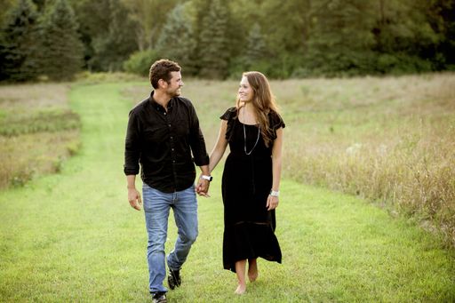 A beautiful shot of a happy couple holding hands and walking in a grassy field with a blurred background