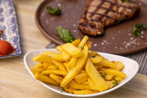 A close-up shot of french fries on a white plate served in a restaurant