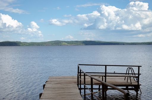 A wooden platform in the lake with green forest across the water