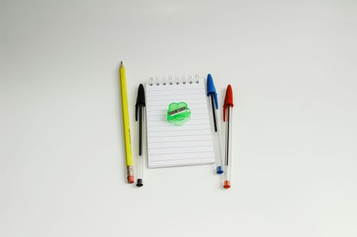 Notepad with a pen, pencil, and sharpener on a wooden desk