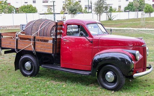 A side view of a classic Studebaker pickup truck with a wooden trunk in a field