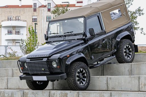A black Land Rover Defender off-road jeep on concrete stairways during an exhibition in a park