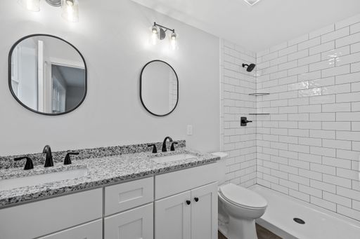 A beautiful modern newly renovated bathroom interior with granite sinks, mirrors, and white walls